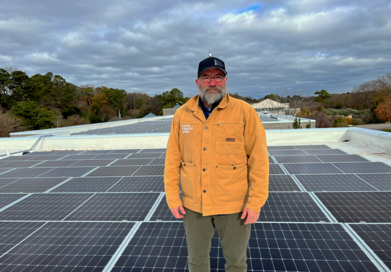 image of Ryan Call Director of Facilities infront of newly installed solar panels at Baker Hall